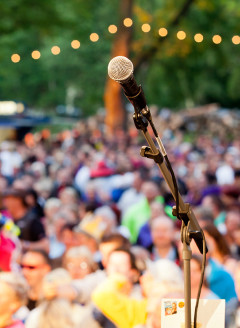 Mikrofon vor einer Menschenmenge bei einer Veranstaltung im Freien.