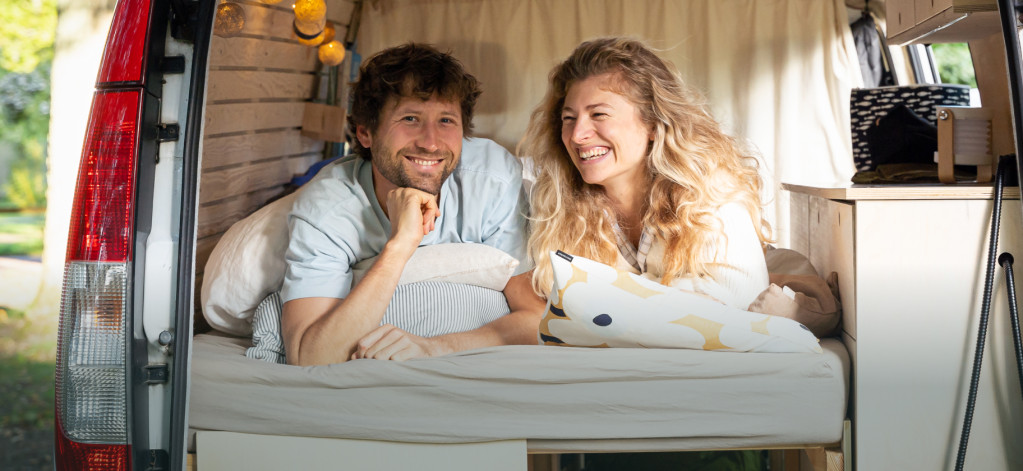 Ein Paar lacht und entspannt in einem Wohnmobil auf dem Campingplatz von Baltic Freizeit in Markgrafenheide.