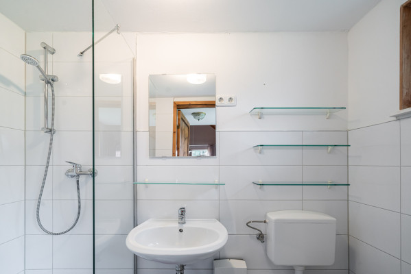 Hell gefliestes Badezimmer mit Dusche, Waschbecken und Spiegel im Campingplatz Baltic Freizeit in Markgrafenheide.