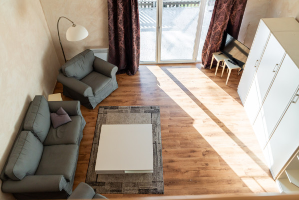 Helles Wohnzimmer mit grauen Sofas, Stehlampe und Zugang zum Balkon bei Baltic Freizeit in Markgrafenheide.