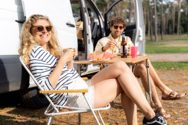 Junges Paar entspannt vor ihrem Wohnmobil, genießt Essen und Trinken auf dem Campingplatz von Baltic Freizeit.