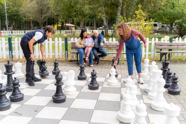 Junge Familie mit Kindern spielt Schach auf einem großen Feld im Außenbereich auf dem Campingplatz von Baltic Freizeit.