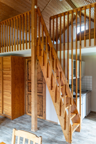 Holztreppe führt zum Obergeschoss einer Hütte mit sichtbarem Küchenbereich im Campingplatz Baltic Freizeit in Markgrafenheide.