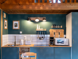 Innenansicht einer Küche mit blauen Schränken, weißen Kacheln und Holzakzenten, ausgestattet mit modernen Küchengeräten.