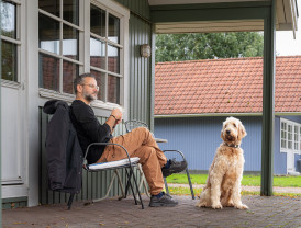Ein Mann entspannt auf einer Terrasse mit seinem freundlichen, flauschigen Hund im Campingplatz Baltic Freizeit in Markgrafenheide.