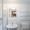 Hell gefliestes Badezimmer mit Dusche, Waschbecken und Spiegel im Campingplatz Baltic Freizeit in Markgrafenheide.