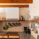 Voll ausgestattete Küchenzeile mit Mikrowelle, Herd, Geschirr, Kaffeemaschine und Hängeutensilien in einer Unterkunft von Baltic Freizeit in Markgrafenheide.