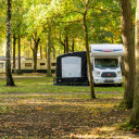Wohnmobil geparkt unter Bäumen auf dem Campingplatz Baltic Freizeit in Markgrafenheide.