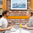 Pärchen sitzt sich lächelnd gegenüber und frühstückt im Restaurant auf dem Campingplatz.